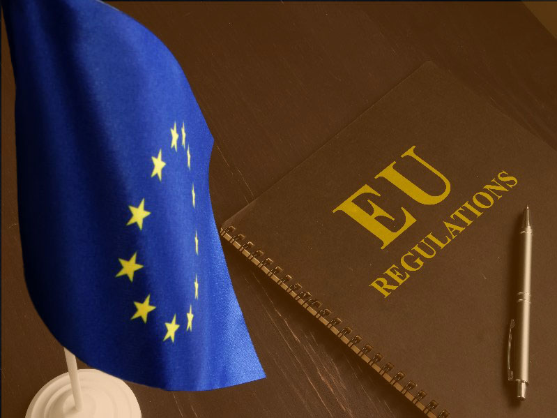 EU-flagga framför en bok med titeln "EU Regulations" och en penna.